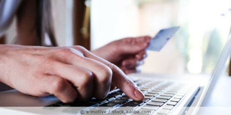 Frau am Laptop hält eine Kreditkarte in der Hand und tippt Daten ein.