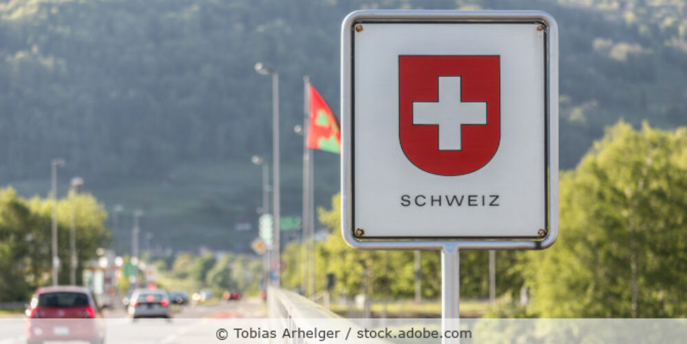 Blick auf ein Schild mit dem Wappen der Schweiz nehmen einer Straße und mit Bergen im Hintergrund.