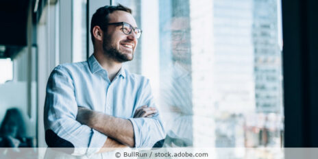 Ein Geschäftsmann lehnt in einem Büro an einer Fensterfront