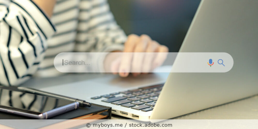 Eine Frau sitzt vor einem Laptop, im Vordergrund ist das Eingabefeld einer Suchmaschine als Illustration zu sehen.