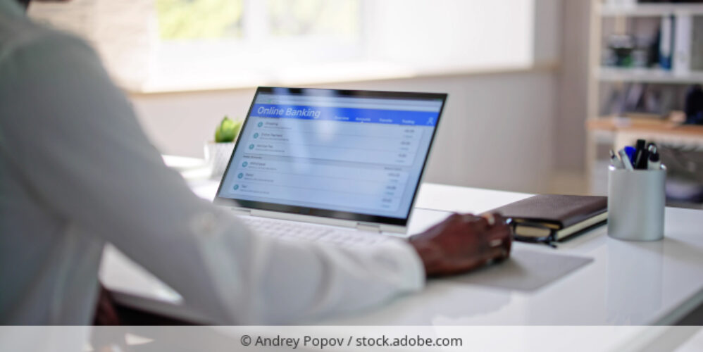 Mann tätigt Online-Überweisung an Laptop.