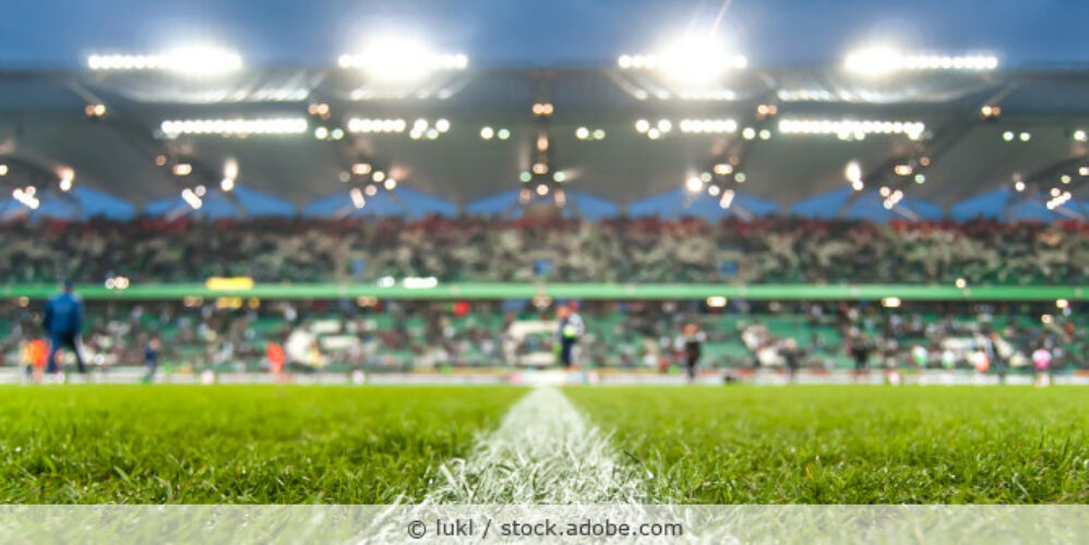 Blick auf ein Fußballspiel im Stadion abends bei Flutlicht.