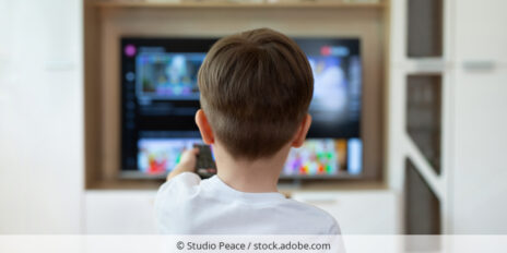 Kind bedient Smart-TV mit Fernbedienung.
