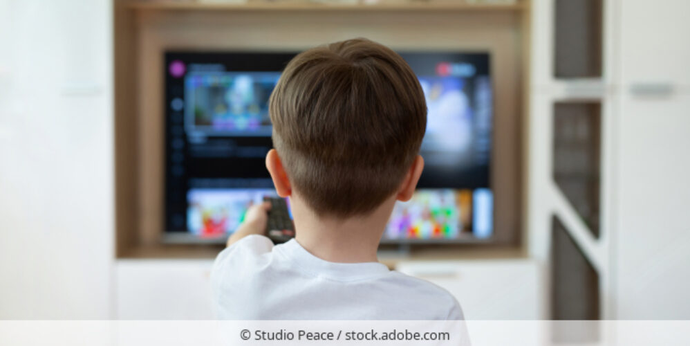 Kind bedient Smart-TV mit Fernbedienung.