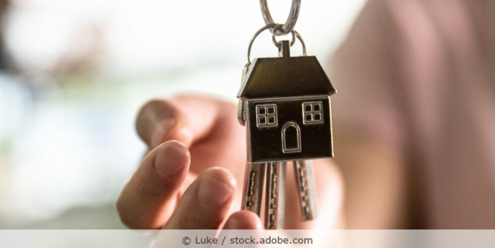 Schlüssel mit Haus-Schlüsselanhänger werden an neuen Bewohner übergaben.