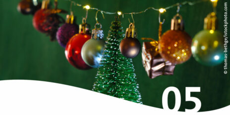 Lichterkette an der bunte Weihnachtskugeln hängen im Vordergrund die Zahl 5
