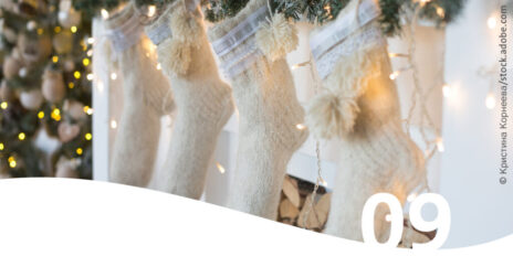Weiße Weihnachtsstrümpfe die vor einem Kamin hängen im Vordergrund die Zahl 9