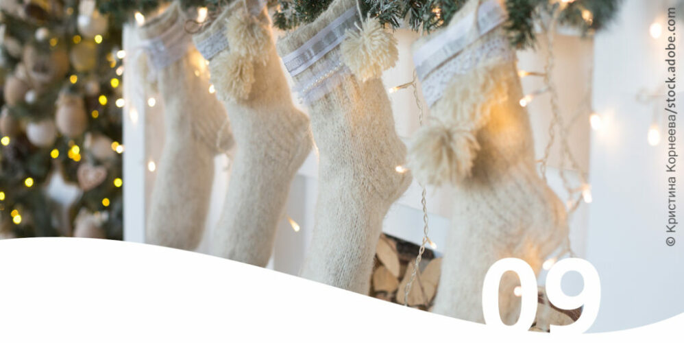 Weiße Weihnachtsstrümpfe die vor einem Kamin hängen im Vordergrund die Zahl 9