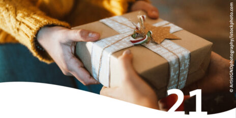 Hände verschenken Weihnachtsgeschenk im Vordergrund die Zahl 21