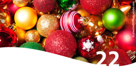 Nahaufnahme bunte Weihnachtsbaum-Kugeln im Vordergrund die Zahl 22