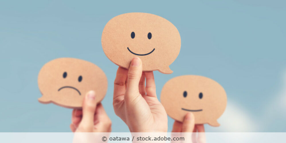 Drei Hände halten Sprechblasen hoch mit unterschiedlichen zufriedenen Smiley-Gesichtern.