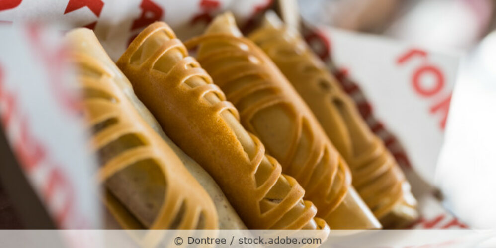 Vier Khanom Tokyo (gefüllte thailändische Crepes) liegen in einer Pappschachtel.