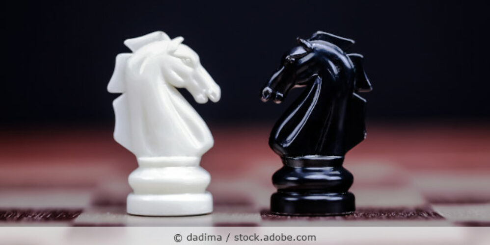 Zwei Schachfiguren stehen sich auf einem Schachbrett direkt gegenüber.