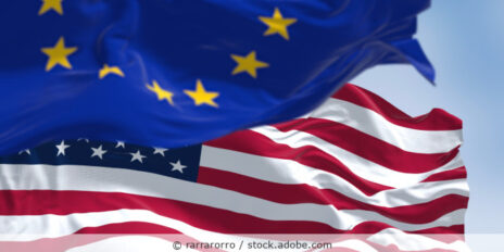 Die Flaggen der EU und der USA vor blauem Himmel.