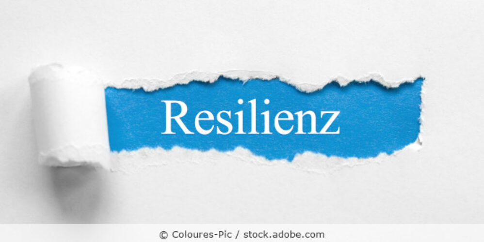 Das Wort Resilienz in weißer Schrift auf blauem Papier gedruckt.