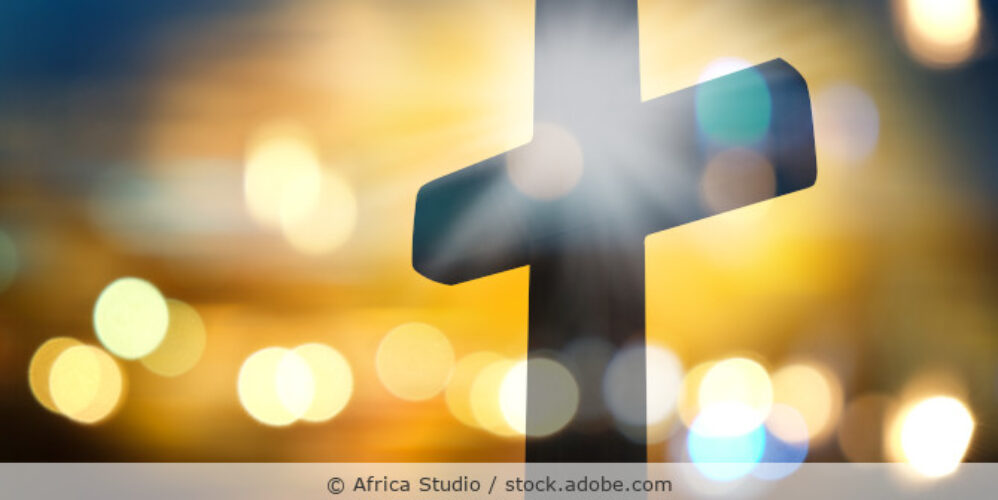 Ein Kreuz und helle Lichter im Hintergrund.