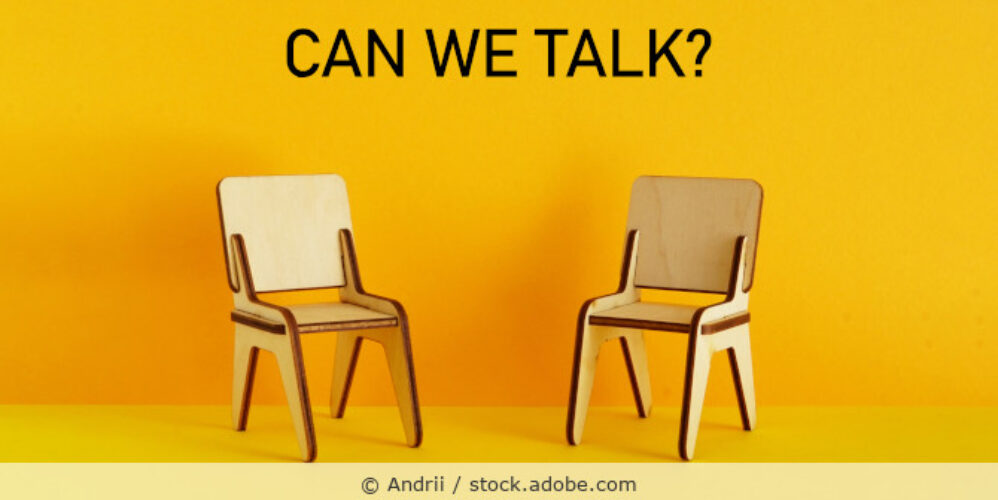 Zwei kleine Holzstühle vor gelbem Hintergrund und dem Text „Can we talk?“.