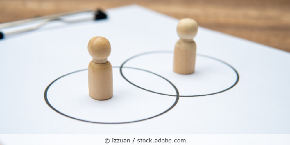 Zwei Holzspielfiguren stehen in sich überschneidenden Kreisen.
