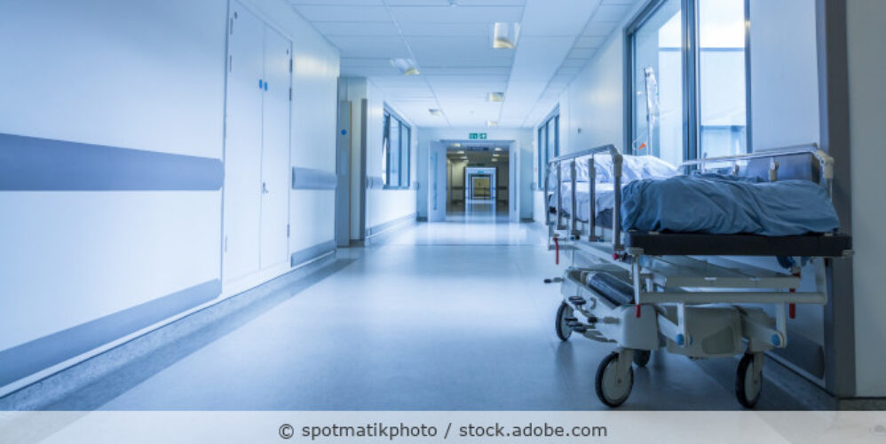 Ein leeren Patientenbett steht auf einem Krankenhausflur.