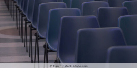 Dunkelblaue Stapelstühle stehen in Reihen in einem Konferenzraum.
