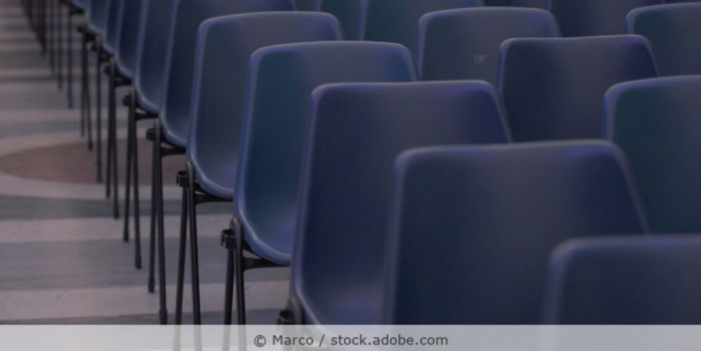 Dunkelblaue Stapelstühle stehen in Reihen in einem Konferenzraum.