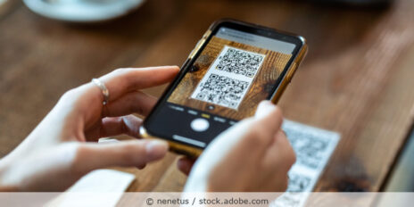 Frau scannt im Restaurant mit dem Handy einen QR-Code zum Bestellen ein.